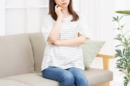 女性がソファに座り考え事をしている