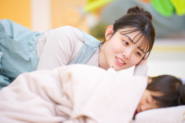 女性が布団で眠る子供を見守る様子