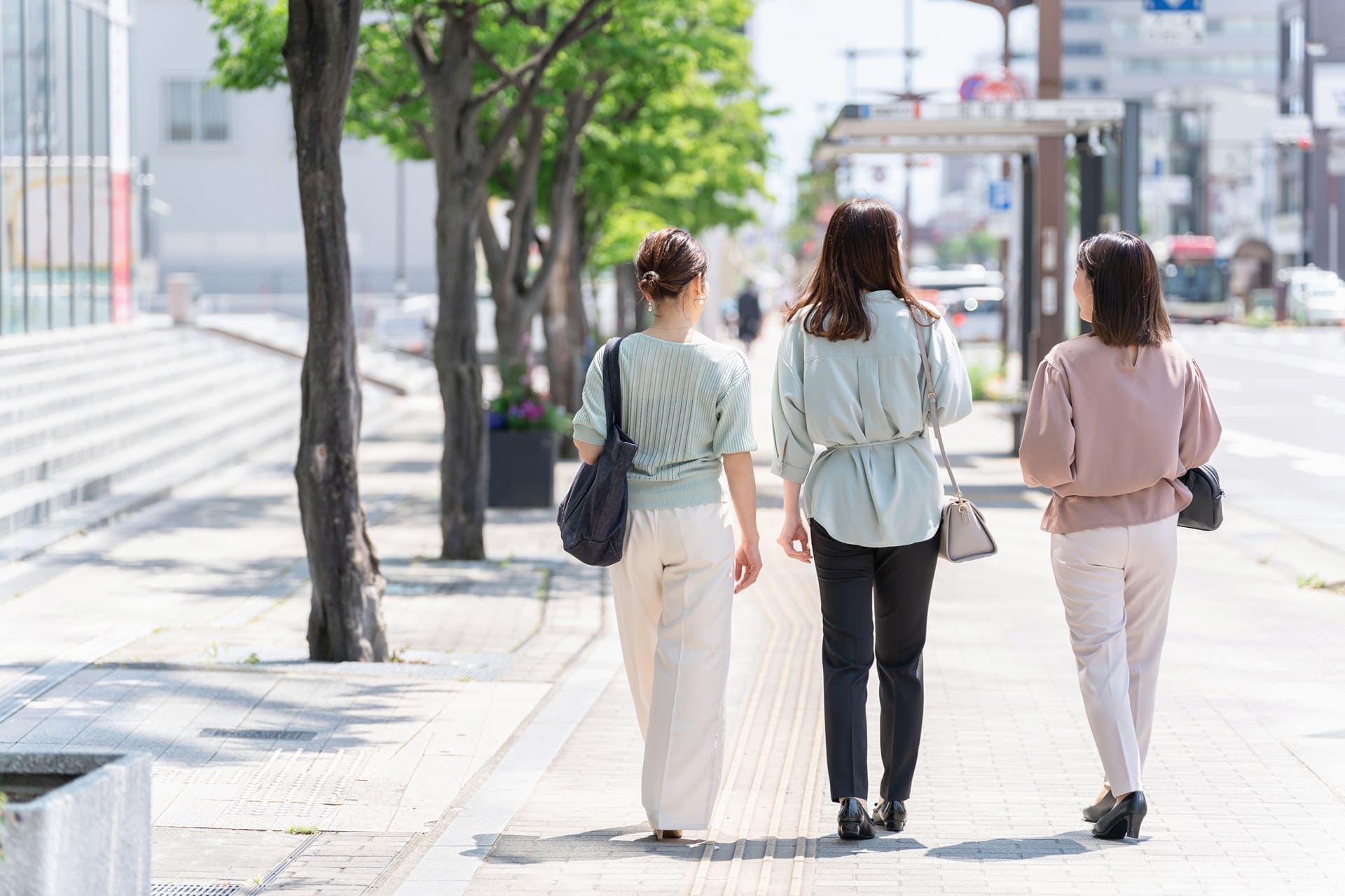 歩道を歩く3人の女性の後ろ姿